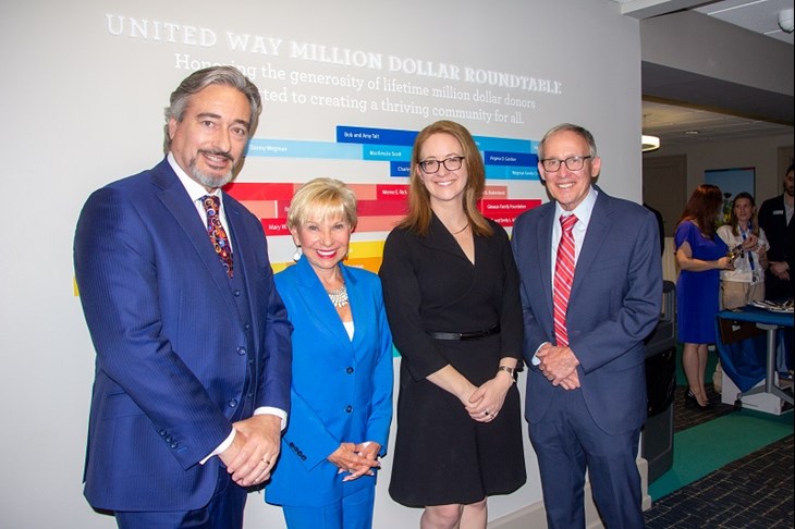 Mike Schwabl, Lauren Dixon, United Way President & CEO Jaime Saunders, and Gary Muisus in front of the Million Dollar Roundtable display at United Way of Greater Rochester and the Finger Lakes